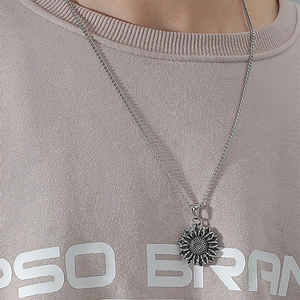 Minimalist silver sunflower pendant necklace worn on a pastel knit sweater