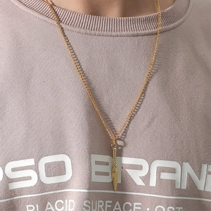 Gros plan d'un collier avec pendentif flèche dorée porté sur un sweat à capuche