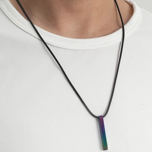 Détail du pendentif barre en acier inoxydable irisé sur un collier cordon noir minimaliste