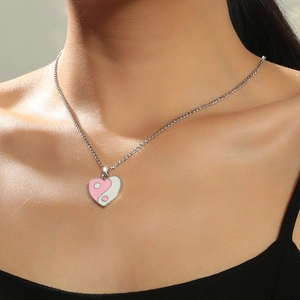 Nahaufnahme der herzförmigen Yin-Yang-Halskette in Rosa und Weiß, von einem Model getragen