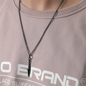 Détail du collier noir avec pendentif pointe de lance pour homme sur un t-shirt imprimé