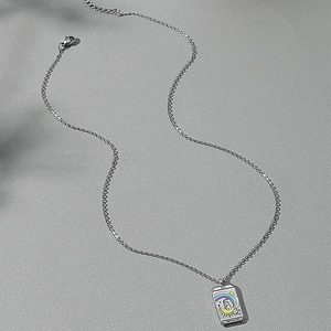 Macro shot of silver tarot card pendant with rainbow and star relief on a chain