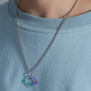 Vue détaillée du pendentif Saturne iridescent sur une chaîne argentée et pull bleu