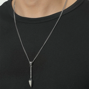 Gros plan du collier pour homme avec pendentif pointe de flèche argentée et chaîne cubaine