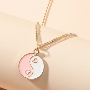 Detail von rosa-weißem Emaille Herz Yin Yang Anhänger an einer goldenen Halskette