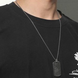 Model wearing a retro metal dog tag necklace with woven texture on a black T-shirt