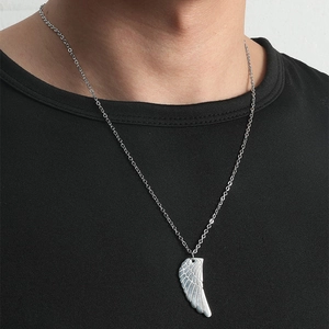 Gros plan du pendentif aile d'ange en argent sur une chaîne fine portée sur noir
