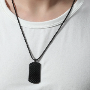 Detail shot of a black military dog tag necklace with diamond pattern on a white t-shirt