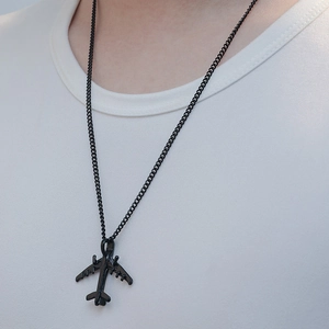 Detailed macro of a black matte airplane pendant on a fine metal chain for men