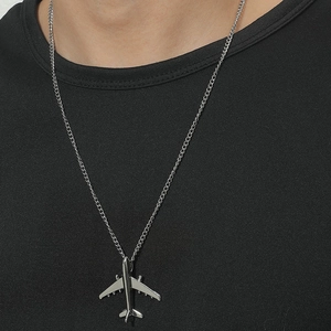 Detail of silver airplane pendant necklace worn on a black shirt for hip-hop style