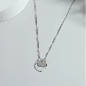Minimalist silver double heart pendant necklace with beaded chain on a grey base