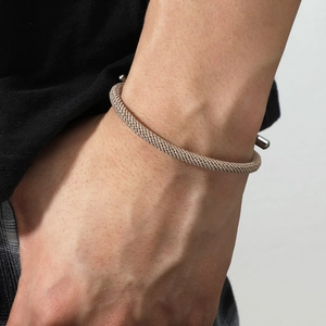 Vue détaillée de la texture métallique tressée et des embouts cylindriques du bracelet