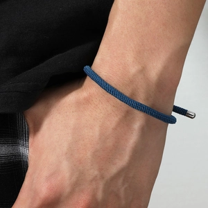 Détail du bracelet en corde tressée bleue avec fermoir métallique sur le poignet