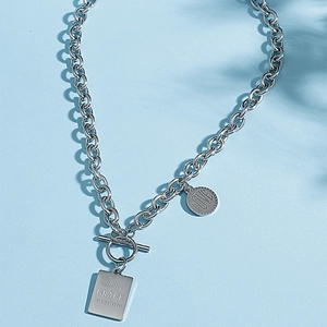 Detail of silver T-bar clasp necklace with engraved rectangular and circular pendants