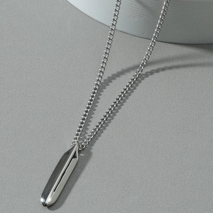 Minimalist silver geometric bullet pendant necklace with high polished finish on gray background