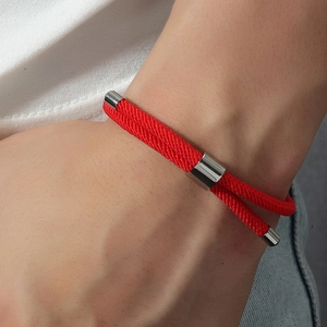 Gros plan d'un bracelet tissé rouge fait main avec des éléments en métal argenté