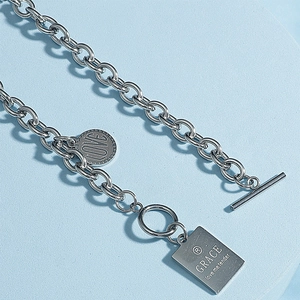 Detail of silver T-bar closure and engraved LOVE charms on chunky stainless steel chain