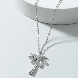 Minimalist silver palm tree pendant necklace with detailed palm leaves on white stand