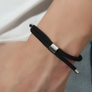 Détail d'un bracelet en corde tressée noire avec fermoir métallique argenté au poignet