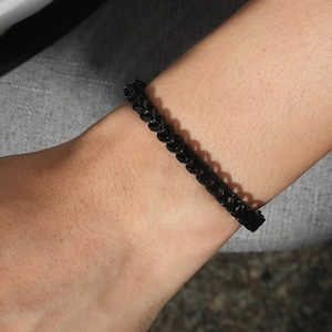 Detailed view of men's black stainless steel wheat chain bracelet worn on wrist