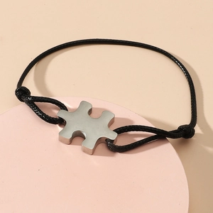 Detail of adjustable black cord bracelet with polished silver puzzle piece pendant