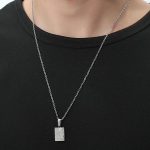 Minimalist silver rectangle pendant necklace with sunburst and moon engraving on black shirt