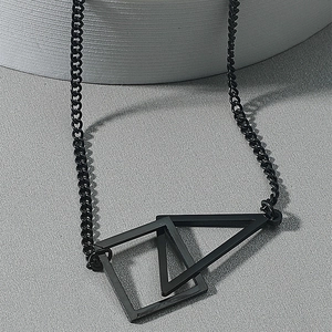 Vue macro du pendentif noir mat en acier inoxydable avec carrés et triangles croisés