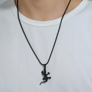 Gros plan d'un collier avec pendentif crocodile noir punk porté sur un t-shirt blanc