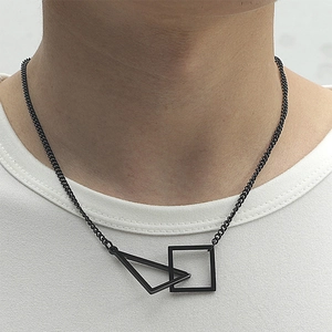 Détail du pendentif géométrique noir mat carré et triangle sur une chaîne gourmette