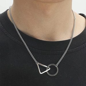 Gros plan d'un pendentif géométrique triangle et anneau sur une chaîne cubaine en acier