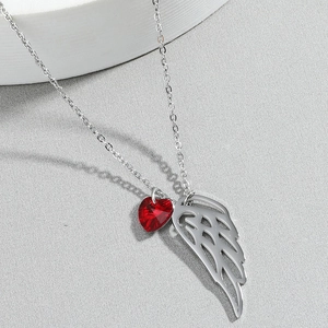 Collana con ali di angelo in argento e ciondolo a cuore rosso su fondo grigio materico