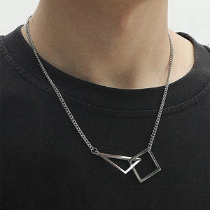 Gros plan d'un collier géométrique en acier titane argenté sur un t-shirt noir