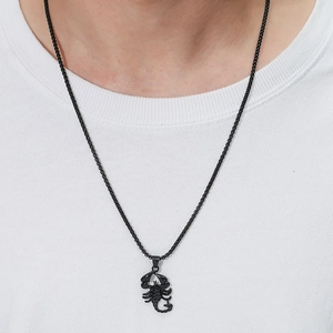 Detailed view of a black scorpion pendant necklace on a plain white t-shirt background