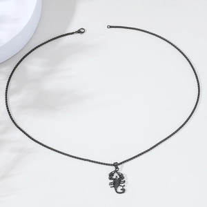 Detailed view of a black scorpion pendant necklace with box chain on a minimalist background