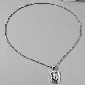 Macro shot of retro silver beetle pendant with intricate box chain detail for men