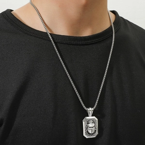 Close-up of vintage silver scarab beetle pendant on chain worn over a black shirt