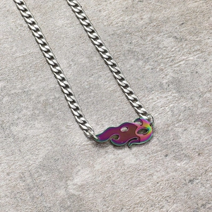 Détail macro du pendentif flamme coloré sur une chaîne cubaine en acier inoxydable argenté