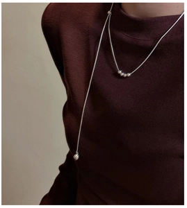 Detail of 925 sterling silver minimalist beaded necklace on burgundy knit sweater