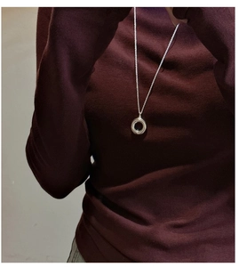 Close-up of minimalist S925 sterling silver hollow ring necklace on a burgundy sweater