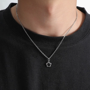 Detail of silver chain necklace with black pentagram star pendant on a male model