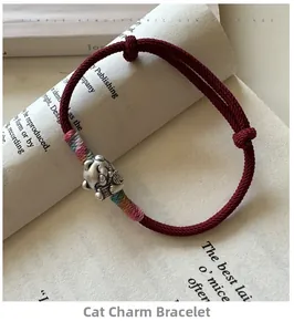 Gros plan d'un bracelet en corde rouge tressée avec pendentif chat de fortune en argent