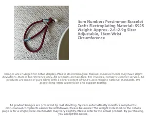 Macro detail of S925 sterling silver persimmon charm on red braided rope bracelet