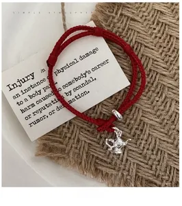 Close-up of S925 silver teapot charm on red woven rope bracelet with adjustable cord