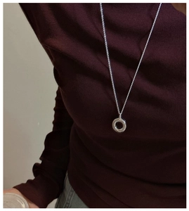 Minimalist silver hollow circle pendant necklace worn on a dark knit sweater background