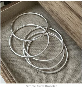 Macro shot of five matte S925 sterling silver minimalist bangles on linen cloth