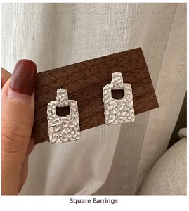 Detailed view of silver square earrings featuring unique textured lava metal surface