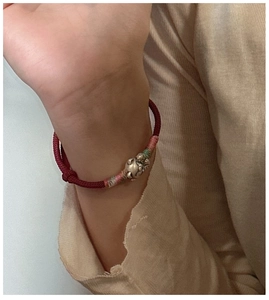 Gros plan détaillé du bracelet en corde rouge avec un pendentif chat porte-bonheur S925