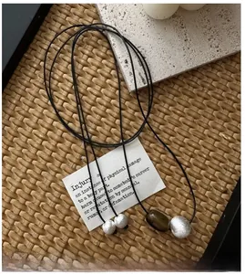 Detailed close-up of S925 sterling silver brushed beads on a black cord necklace