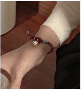 Close-up of S925 sterling silver red cord bracelet with a metal bell on a wrist