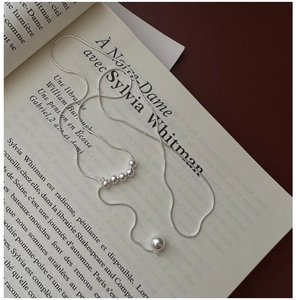 Detailed view of a 925 sterling silver long necklace with a single pearl on an open book